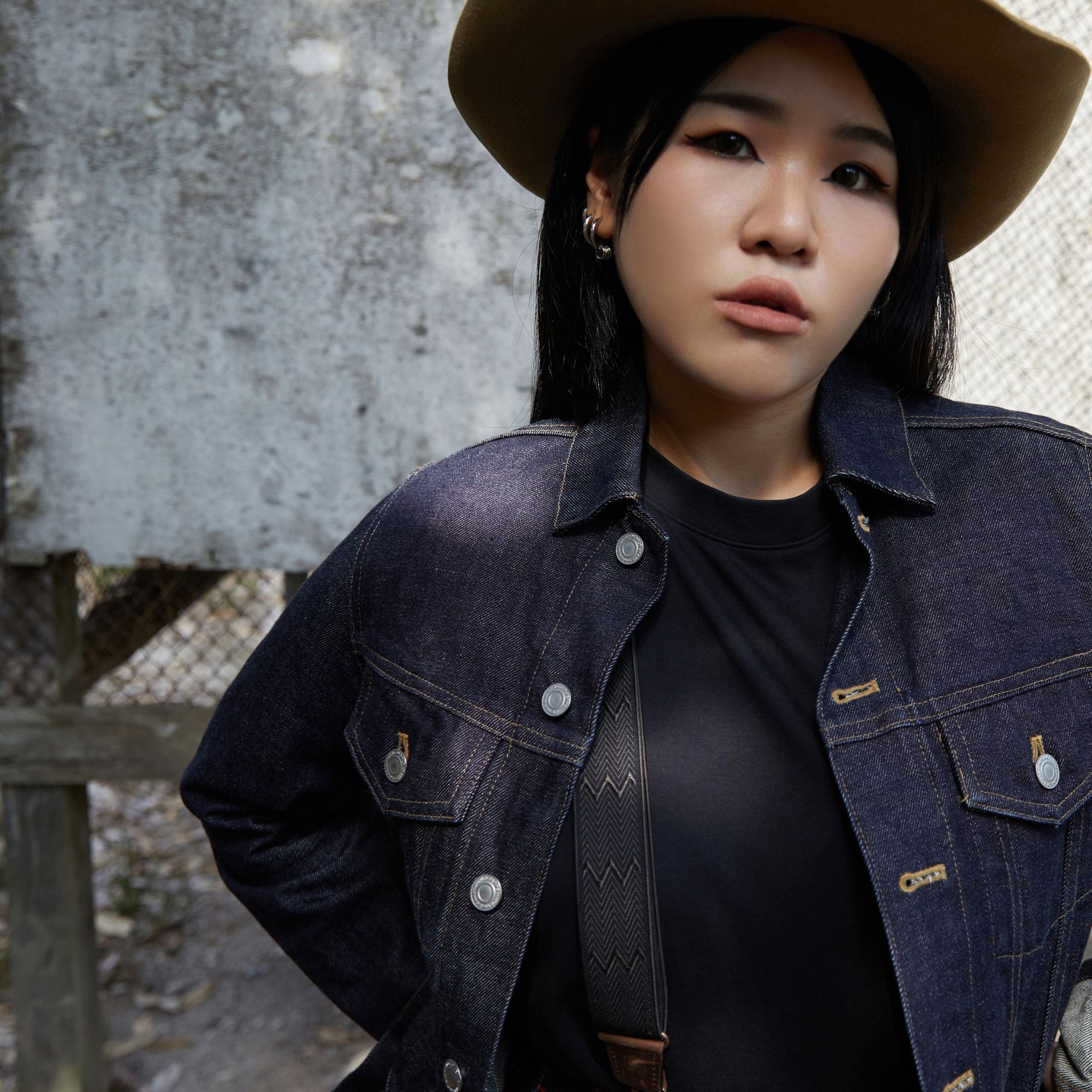 Mina wearing a cowboy hat, denim jacket and Wiseguy Original herringbone pattern elastic suspenders.