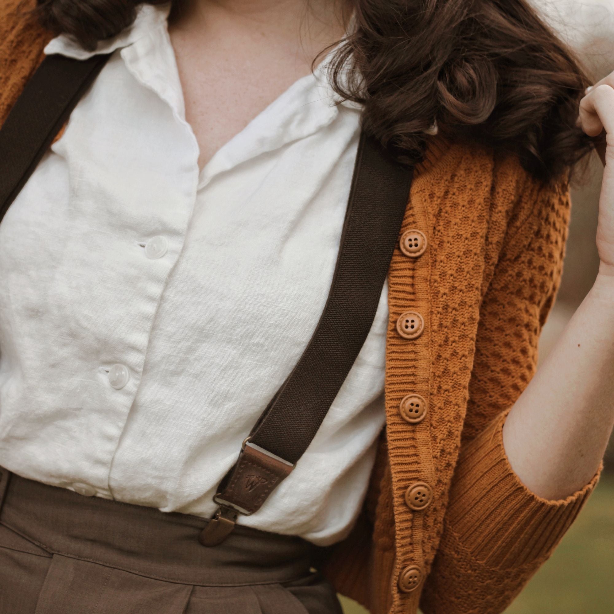 Close-up of Bethany wearing a white blouse, mustard cardigan and brown Wiseguy Original Suspenders.