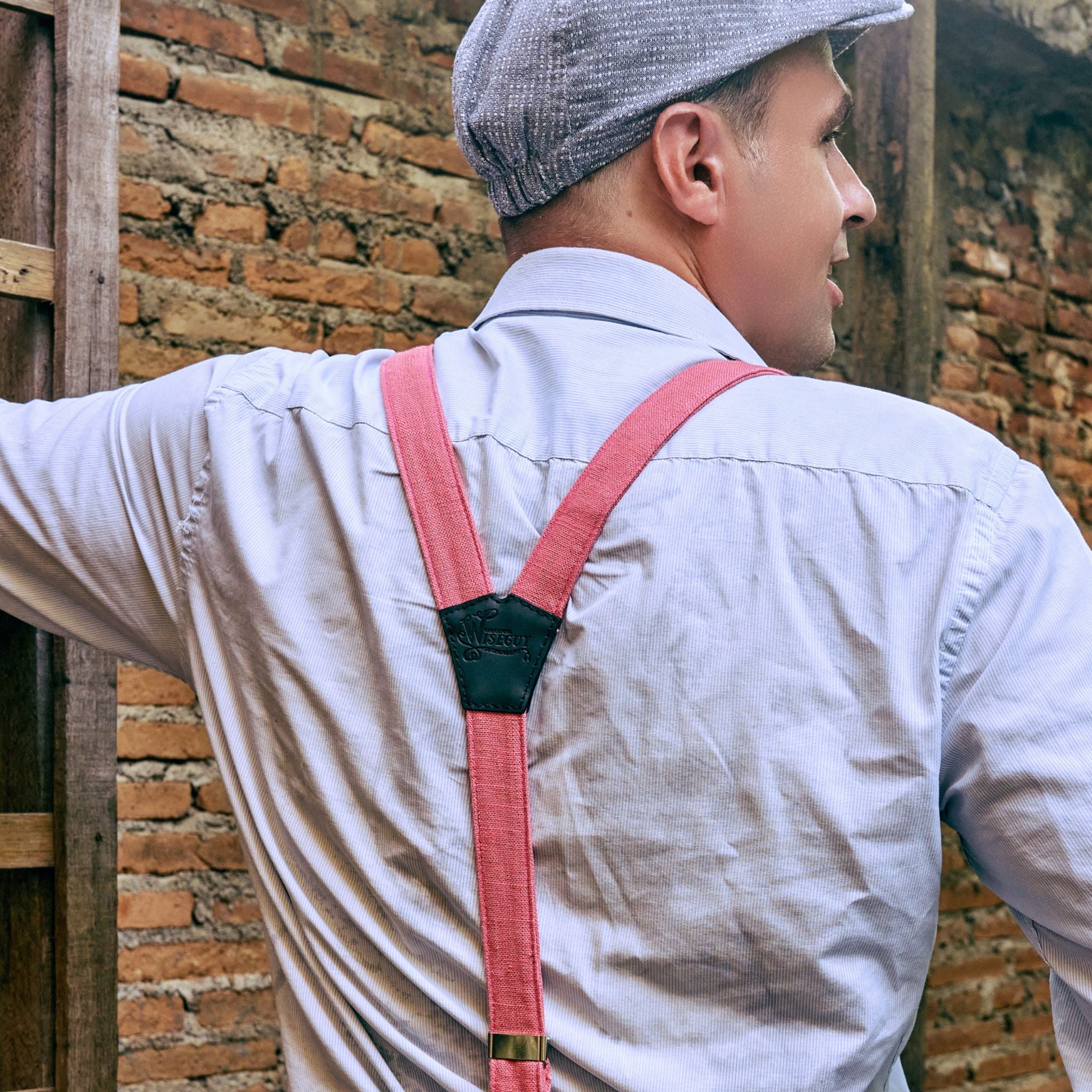 Back of man wearing a subtly striped shirt, flatcap and pink Suspenders.