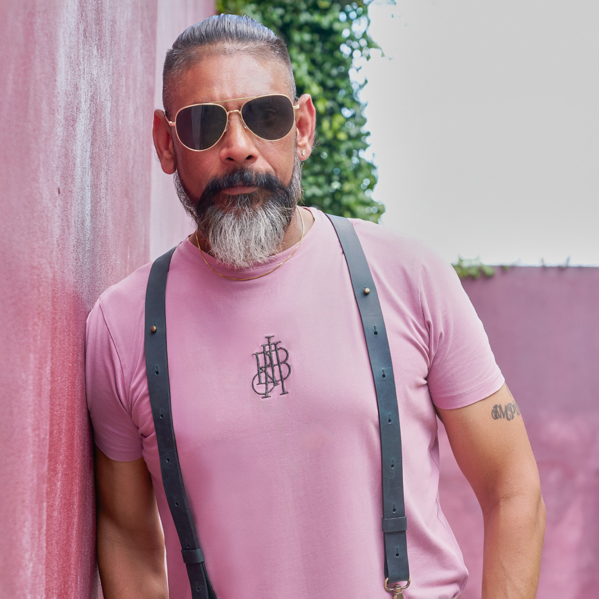 Man wearing leather suspenders, a pink shirt and sunglasses