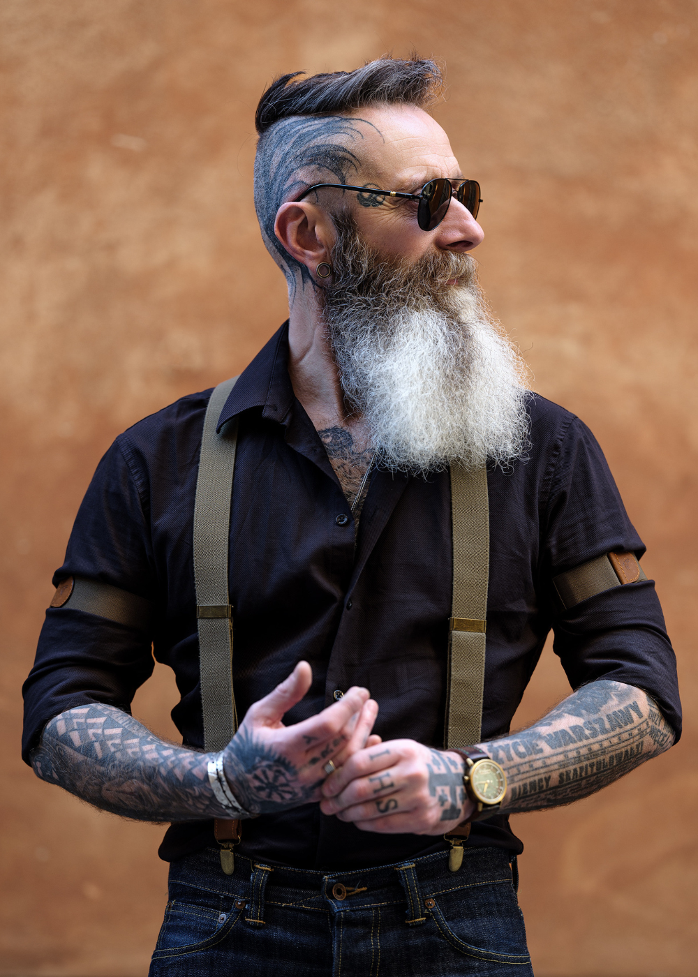 Man wearing Army Green Wiseguy Original Suspenders and Sleeve Garters, a black shirt and aviator sunglasses